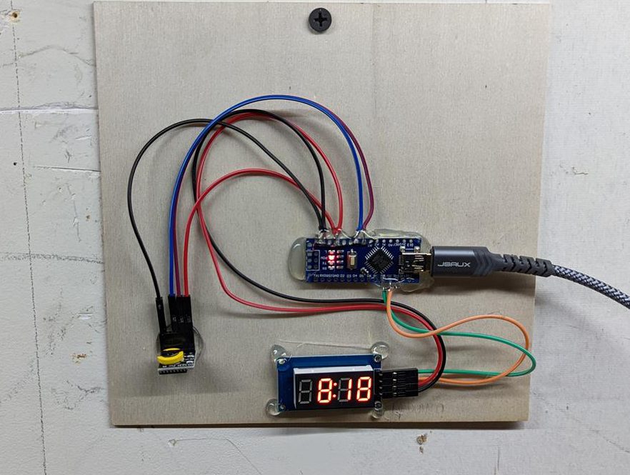 Digital clock components mounted on plywood with hot glue, attached to the wall with a single drywall screw.